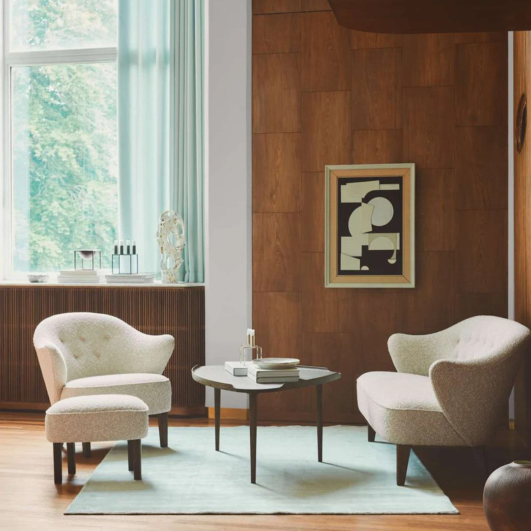 Cozy living room with soft beige chairs, a light blue rug, and a wooden accent wall. Modern art enhances the setting.
