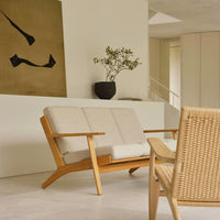 Light beige sofa with natural wood accents, complemented by a woven chair and minimalist, neutral decor.