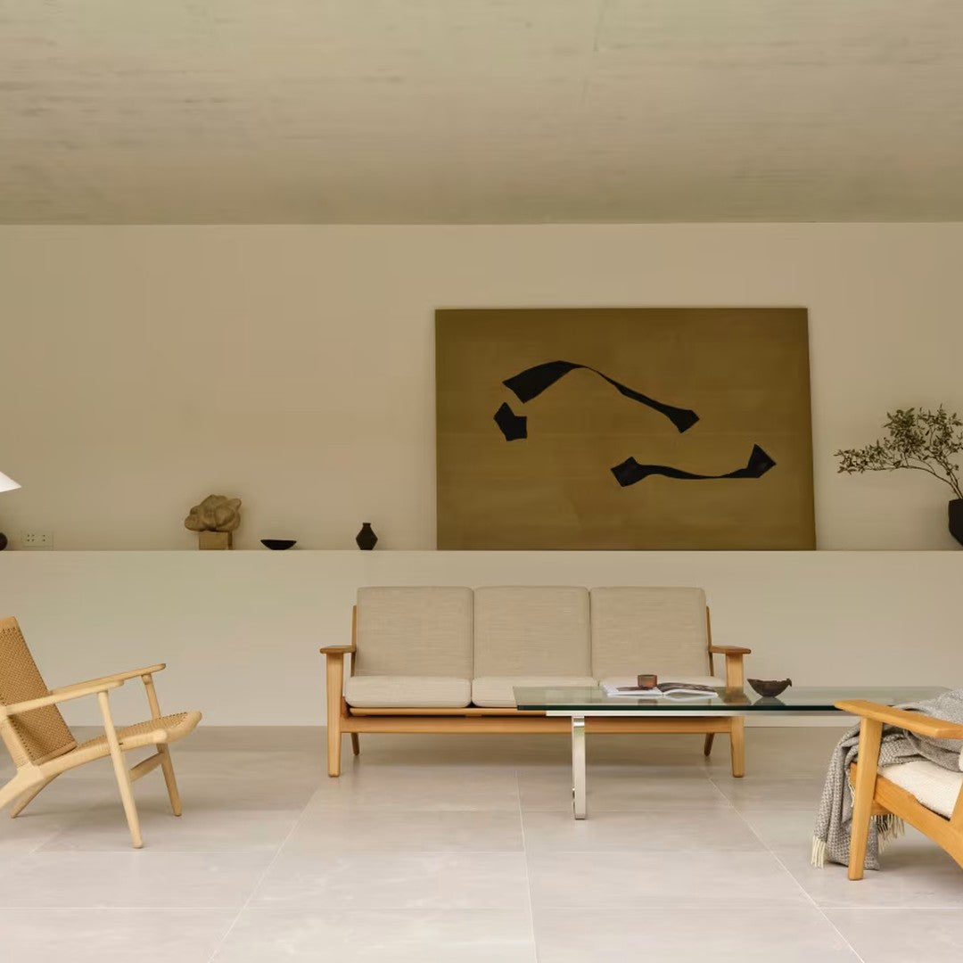 Modern living room featuring neutral tones, earthy beige walls, and bold black abstract art. Clean lines and minimalist design.