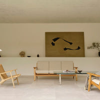 Modern living room featuring neutral tones, earthy beige walls, and bold black abstract art. Clean lines and minimalist design.