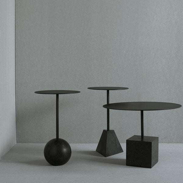 Three modern black side tables with varying shapes: a round top on a sphere, a round top on a pyramid, and a square base.