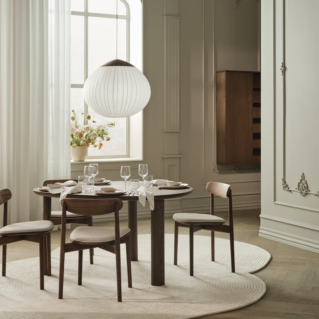 Modern dining room with a round dark wood table, light beige chairs, and a soft beige rug, accented by pastel wall colors.