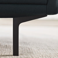 Dark green upholstered sofa with sleek black metal legs on a light carpet.