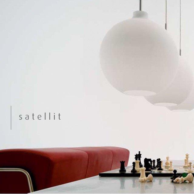 White pendant lamps hang above a sleek red sofa and a classic chess set, creating a modern and minimalist aesthetic.