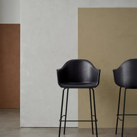 Modern black bar stools against a backdrop of muted beige and earthy brown walls, showcasing minimalist design and colors.