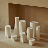 Set of neutral-colored ceramic vases in various geometric shapes, showcasing soft white and beige tones.