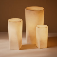 Set of three soft beige ceramic lamps with smooth, cylindrical and geometric shapes, creating a warm, ambient glow.