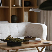 Textured cream sofa with light wood accents, featuring soft buttons and surrounded by neutral decor elements.