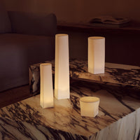 Soft white illuminated candle holders on a marbled table, creating a warm and cozy ambiance.