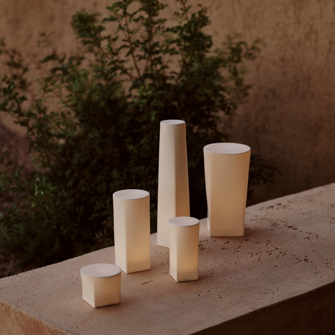 Elegant neutral-colored candle holders in various geometric shapes, showcasing soft, warm illumination against earthy tones.