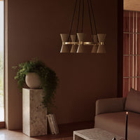 Modern pendant light in muted beige with sleek black accents, set against a warm brown backdrop.