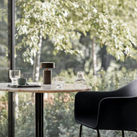 "Elegant black chair, clear glassware, and sleek wooden lamp create a modern, natural color palette."
