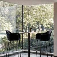 Black bar stools with sleek lines against a backdrop of vibrant greens and soft natural light, creating a modern look.
