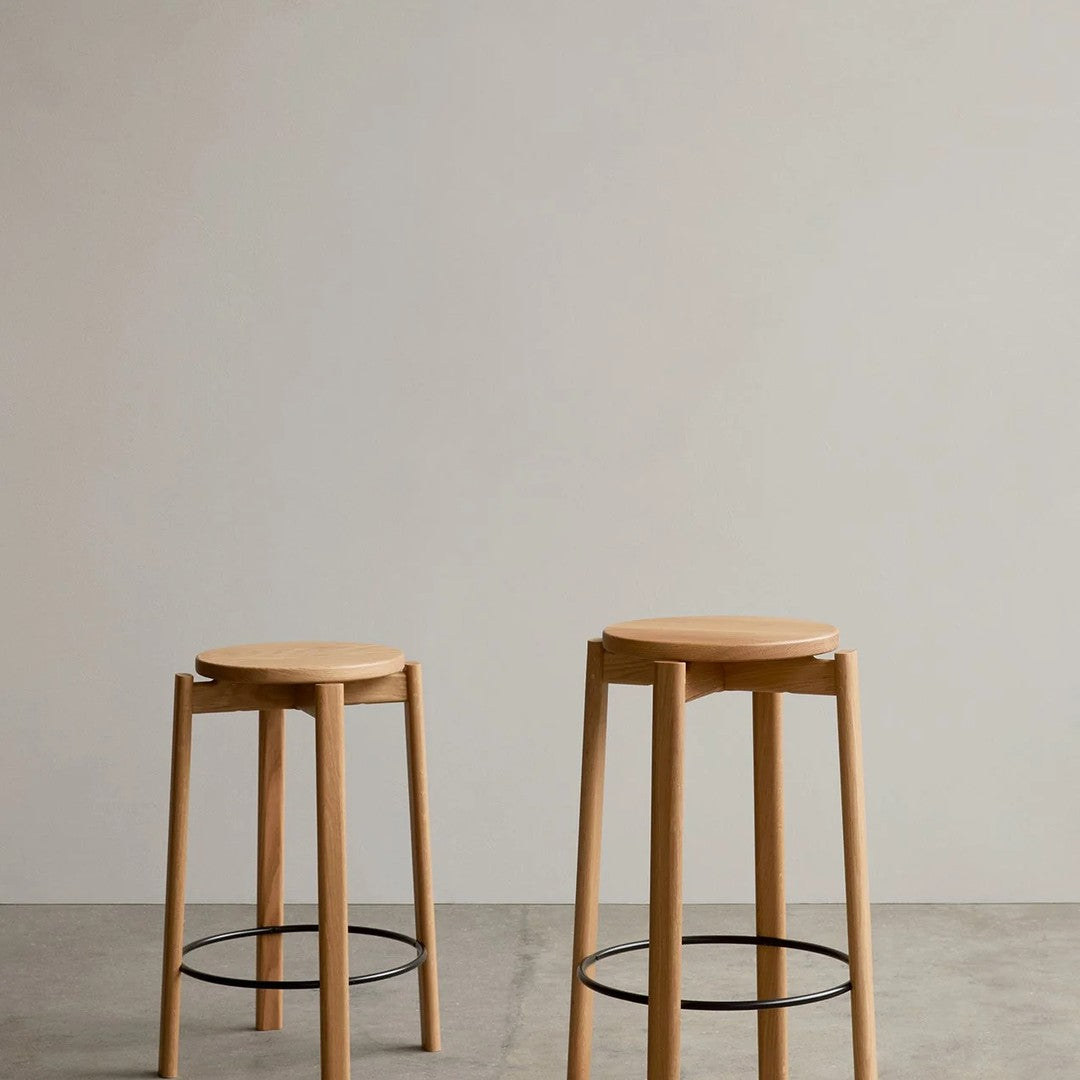 Natural wood bar stools with a smooth finish and minimalist design, featuring light beige tones and black metal accents.