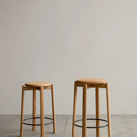 Natural wood bar stools with a smooth finish and minimalist design, featuring light beige tones and black metal accents.