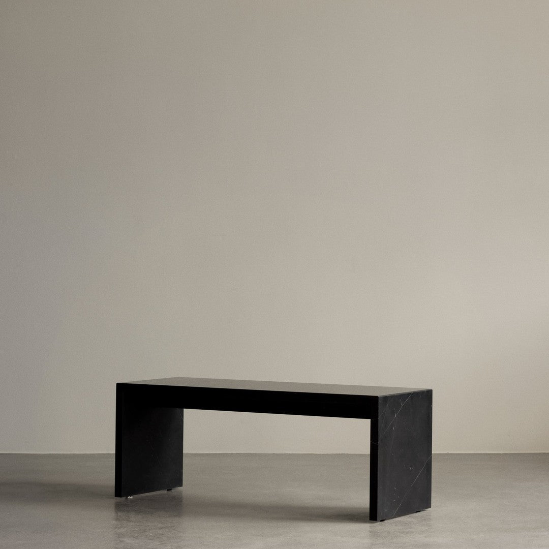"Minimalist black bench with a smooth, matte finish against a neutral background."