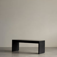 "Minimalist black bench with a smooth, matte finish against a neutral background."