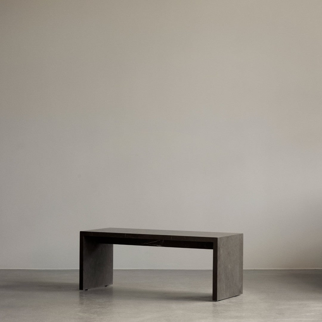 Sleek, modern bench in a minimalist dark gray finish, showcasing clean lines and a smooth surface.