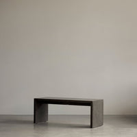 Sleek, modern bench in a minimalist dark gray finish, showcasing clean lines and a smooth surface.
