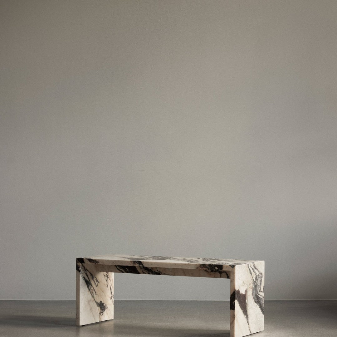Elegant black and white marble bench with striking veining, set against a minimalist gray backdrop.