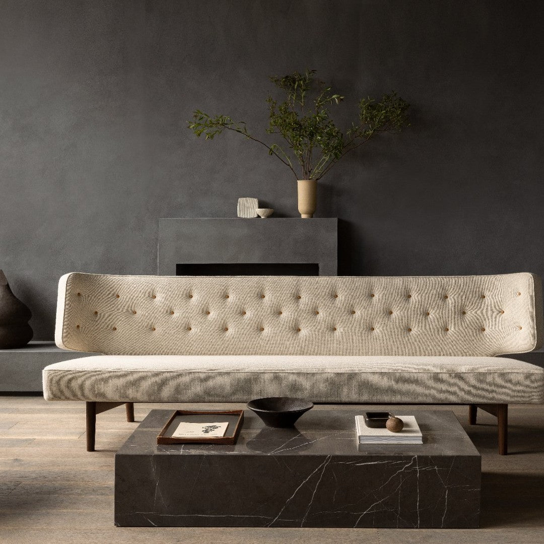 Elegant cream sofa with tufted fabric, paired with a dark marble coffee table against a muted gray backdrop.