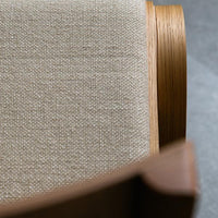 Beige textured fabric on ergonomic chair, complemented by warm wood accents, featuring clean lines and modern design.