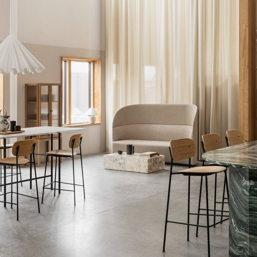 Neutral beige sofa paired with minimalist black and wood dining chairs, set against soft, warm curtain tones.