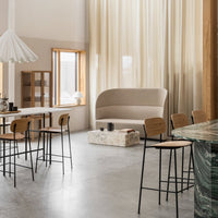 Neutral beige sofa paired with minimalist black and wood dining chairs, set against soft, warm curtain tones.