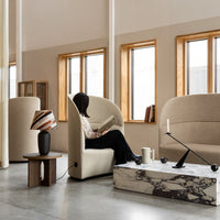 Beige upholstered chairs with soft curves, contrasting black and white marble coffee table, and vibrant patterned lampshade.