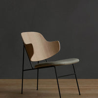 Modern chair featuring a light wood back, grey seat cushion, and black metal legs against a dark background.