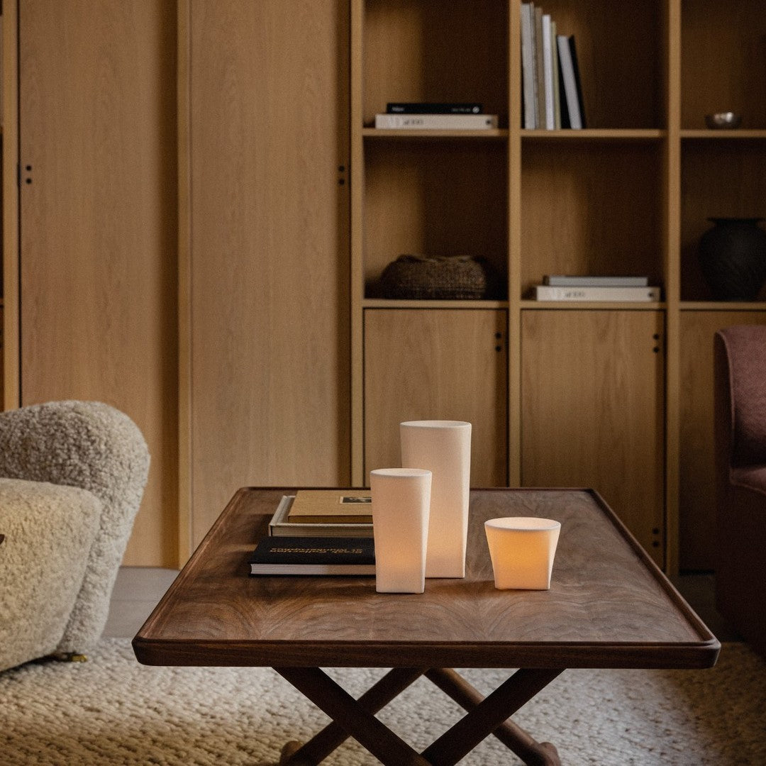 Neutral tones with warm wood, soft textures, and minimalist candle designs create a cozy, inviting atmosphere.