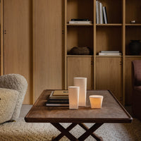 Neutral tones with warm wood, soft textures, and minimalist candle designs create a cozy, inviting atmosphere.