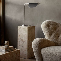 Stylish beige and cream textures on a soft armchair with a sleek metal lamp on a neutral pedestal. Modern home decor.