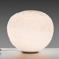 White honeycomb-patterned lamp with a soft glow, featuring a round, textured design against a gray background.