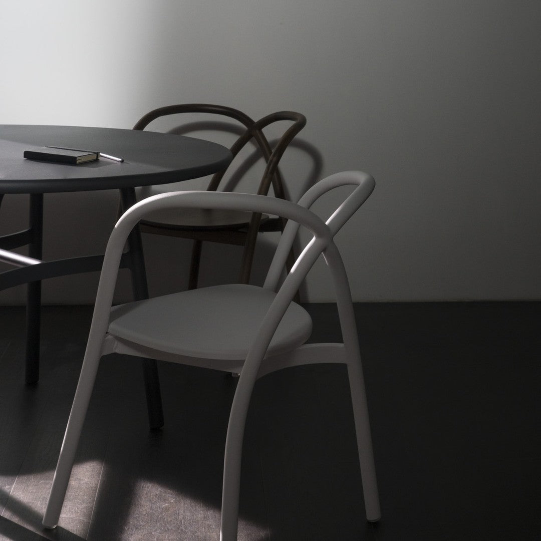 Minimalist grey table with white and brown chairs, featuring smooth curves and a subtle light and shadow play.