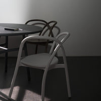 Minimalist grey table with white and brown chairs, featuring smooth curves and a subtle light and shadow play.