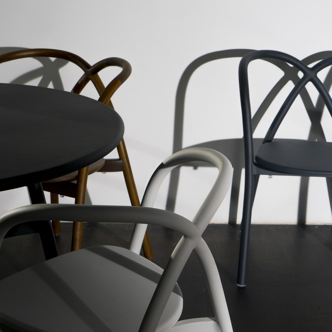 Set of modern chairs in black, gray, and brown, featuring sleek lines and unique shadow patterns on a minimalist background.