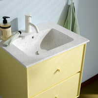 Yellow vanity cabinet with speckled white sink and soft green accents, creating a modern and fresh bathroom aesthetic.