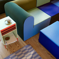Multicolored modern seating in green, blue, and purple with a patterned rug and stylish side table.