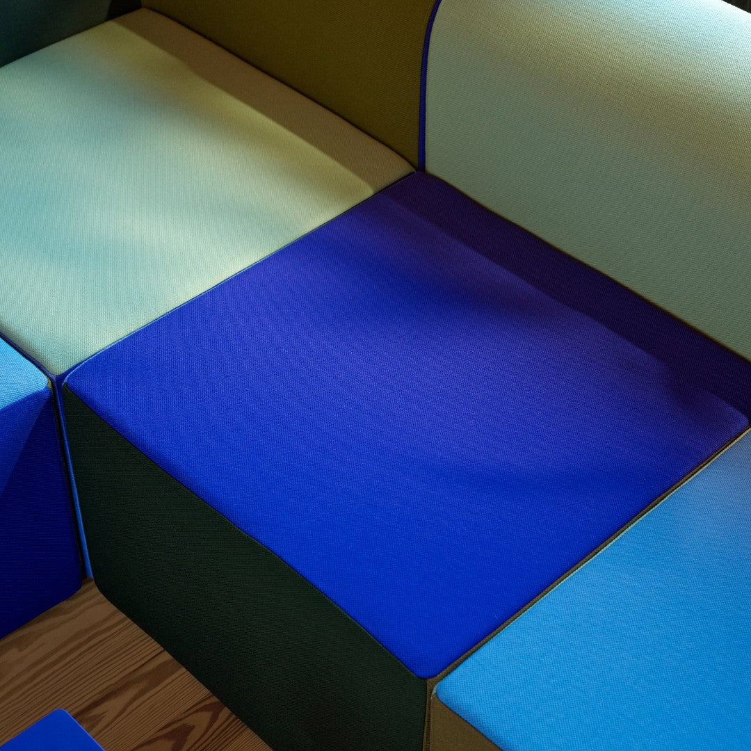 Colorful modular couch section featuring shades of blue, green, yellow, and purple in a geometric pattern.