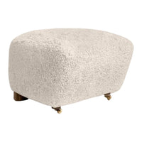 Creamy white, plush textured ottoman with rounded edges and brass caster wheels. Perfect for stylish decor.
