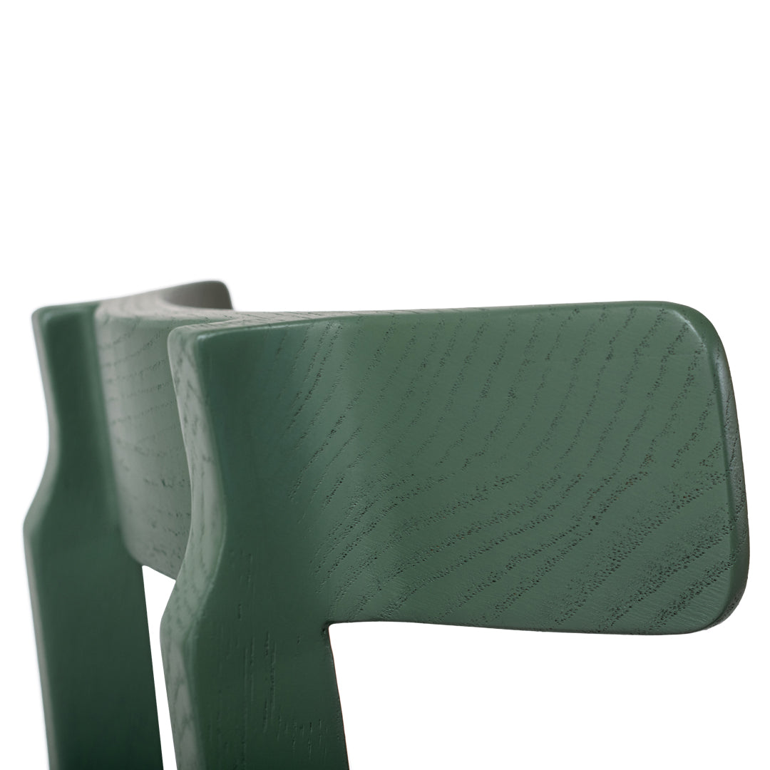 Green wooden chair back with a smooth texture and natural grain pattern, showcasing a contemporary design.