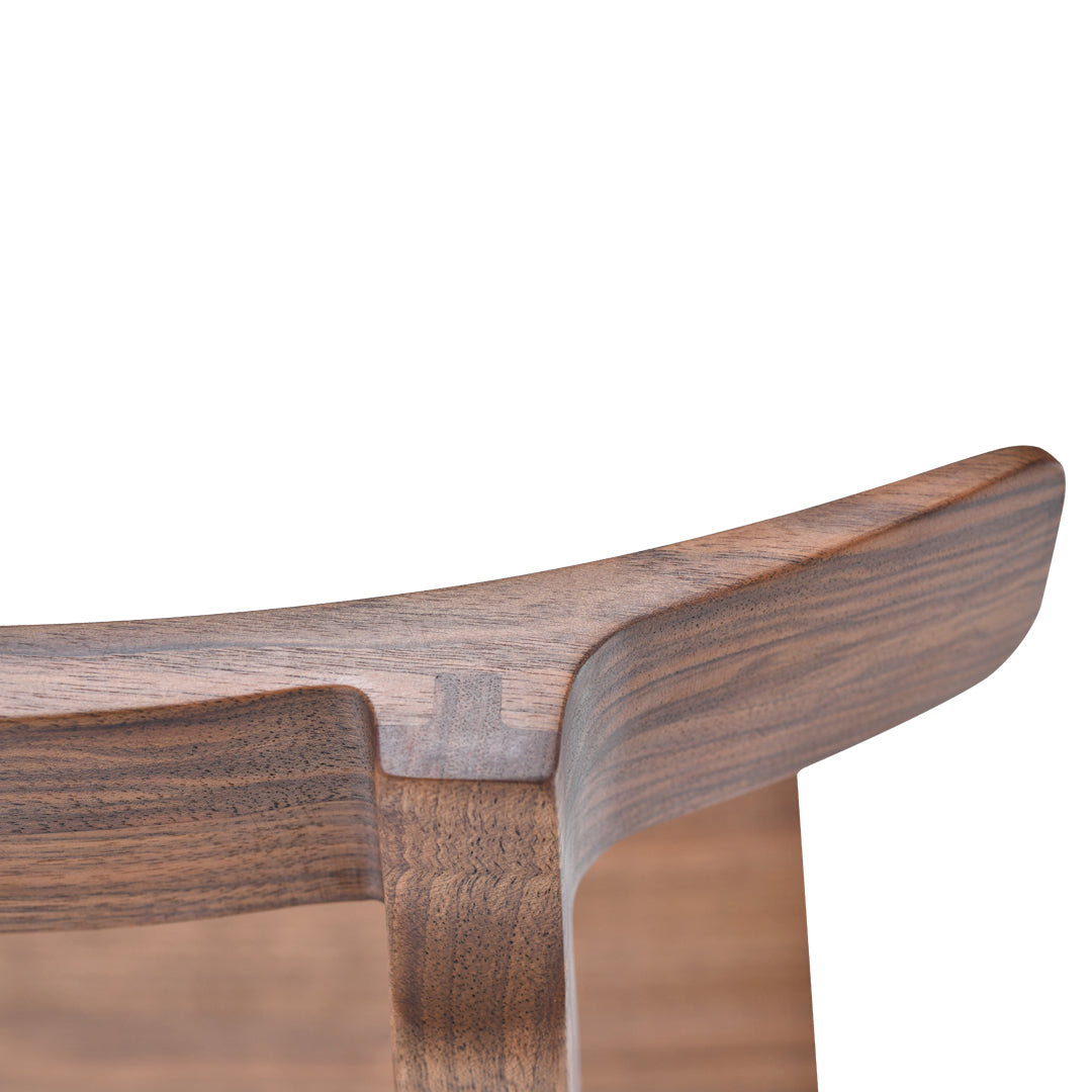 Close-up of a smooth walnut wood surface featuring a rich brown color with subtle grain patterns.