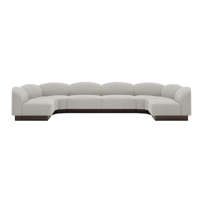 Luxe curved sectional sofa in soft beige upholstery with a sleek dark wood base. Modern, minimalist design.