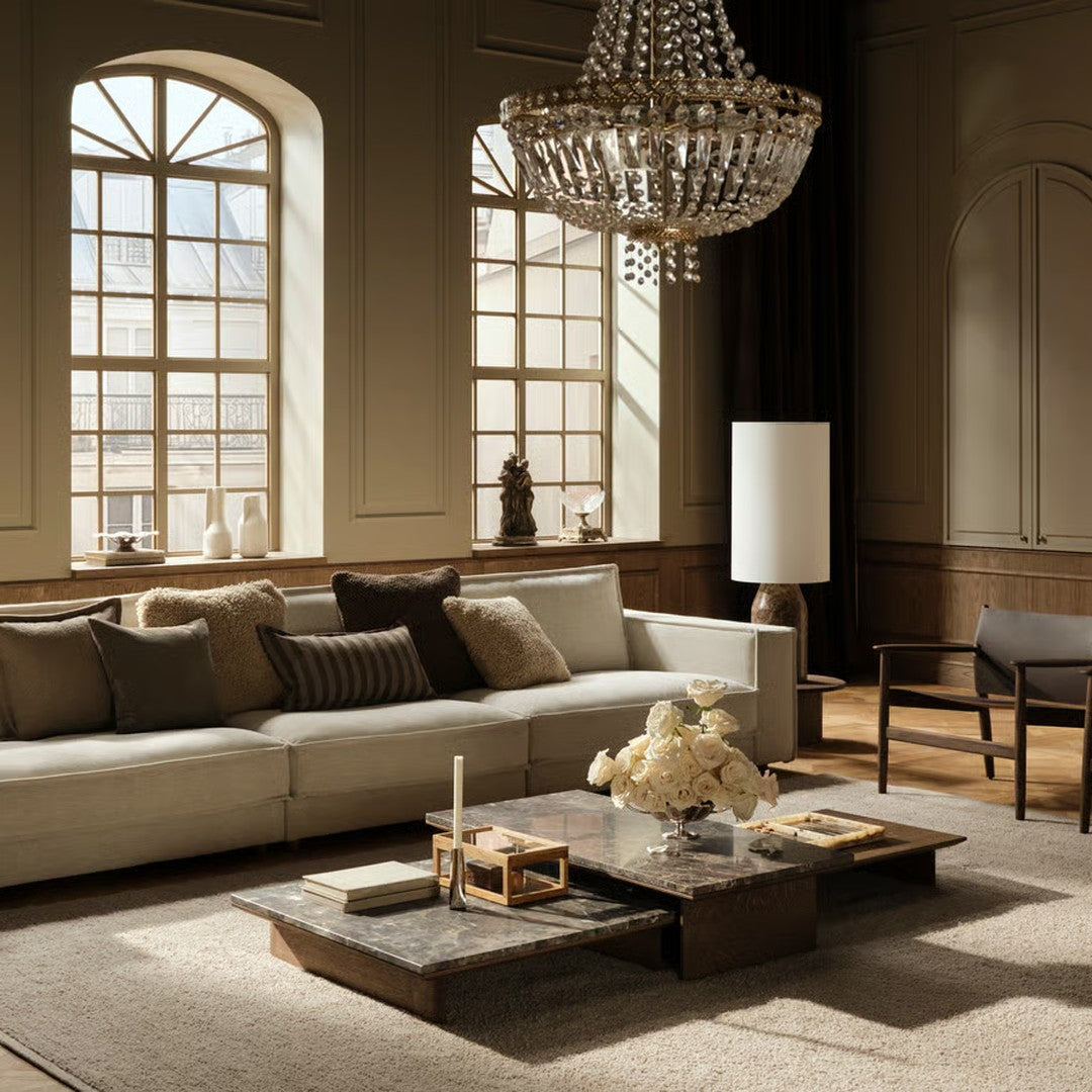 Elegant beige and gray sofa with textured pillows, complemented by a dark wood coffee table and light rug.