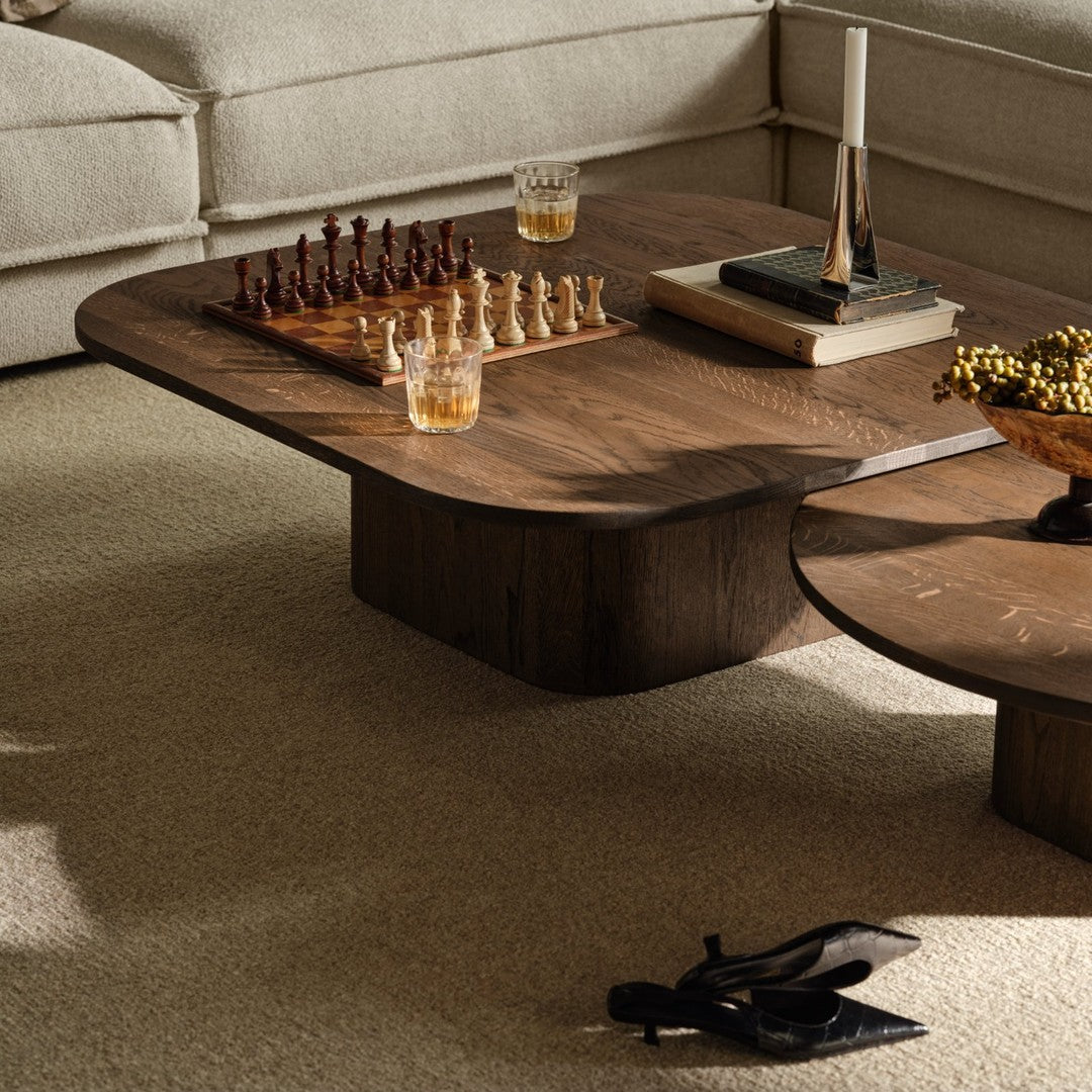 Stylish walnut coffee table with smooth contours, featuring rich brown tones and a sleek, modern design.