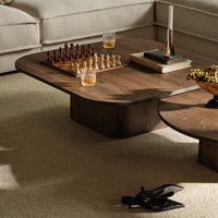 Stylish walnut coffee table with smooth contours, featuring rich brown tones and a sleek, modern design.