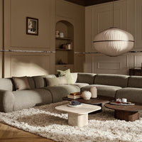 Beige and soft gray sectional sofa with textured fabric, paired with round coffee table and plush white rug.