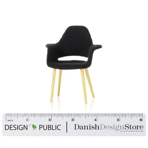 Compact black chair with wooden legs, showcasing a sleek, minimalist design and a smooth finish. Perfect for modern décor.