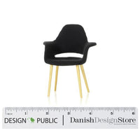 Compact black chair with wooden legs, showcasing a sleek, minimalist design and a smooth finish. Perfect for modern décor.